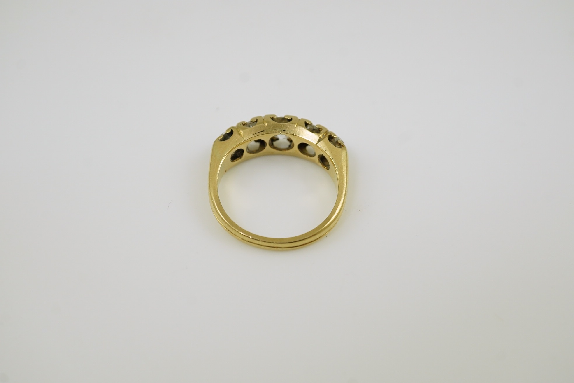 An antique gold and graduated five stone old mine cut diamond set half hoop ring